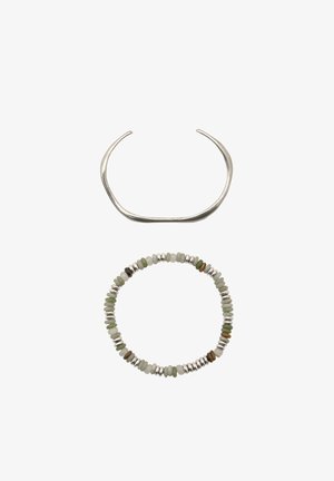 Zilveren armband met een gebogen ontwerp boven een kralenarmband met groene en zilveren accenten, afgewisseld met schijven in aardetinten.