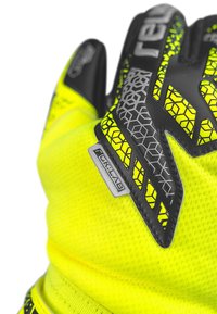 Gelbe Handschuhe aus strukturiertem Stoff, mit schwarzen Akzenten und einem geometrischen Muster. Mit einem Etikett "GK-LAB" im Bereich des Handgelenks.