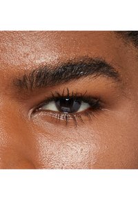 Primo piano di un occhio marrone con lunghe ciglia scure e sopracciglia ben curate. La pelle attorno all'occhio ha una consistenza liscia e leggermente luminosa.