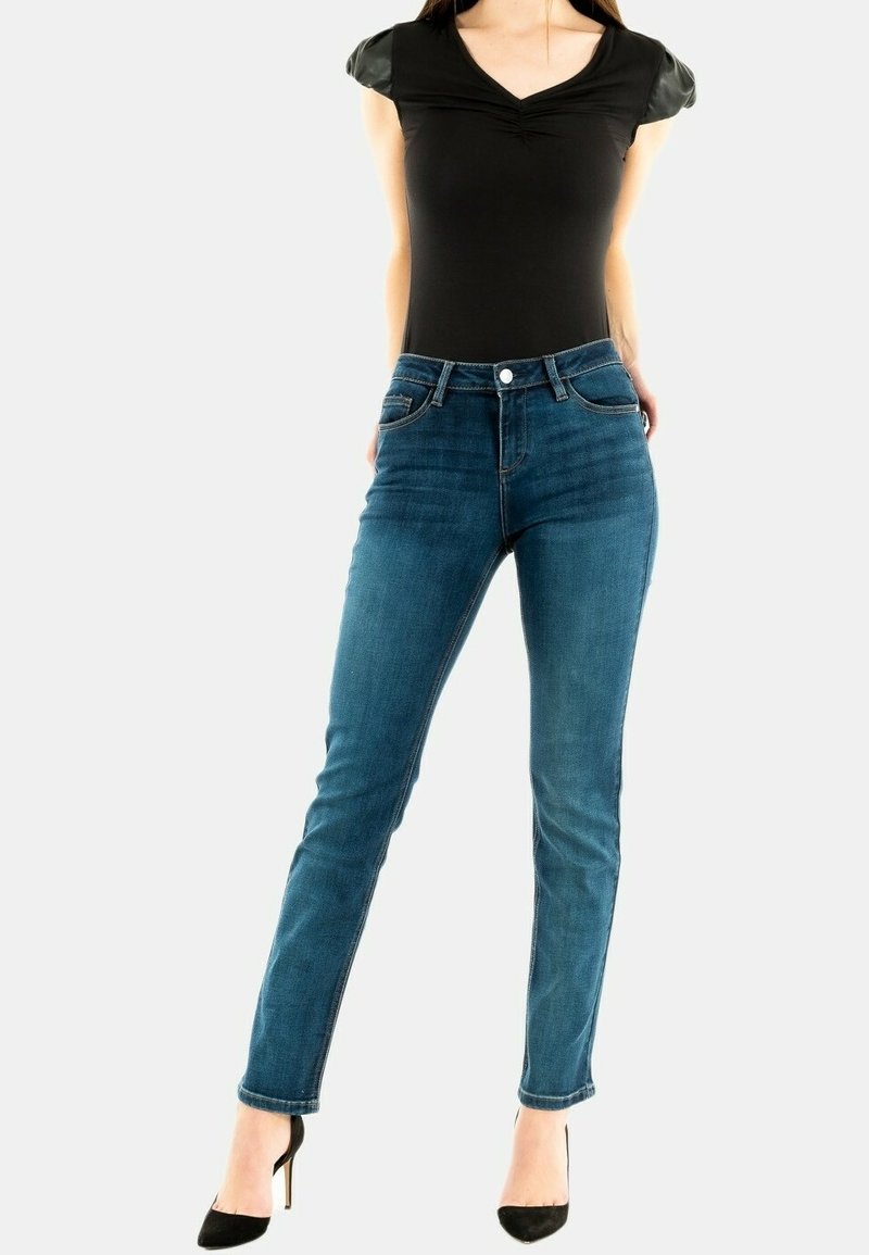 Bodysuit negro con mangas cortas y ajustadas. Pantalones vaqueros ajustados de mezclilla azul, de tiro alto con una textura suave, que presentan un botón delantero y detalles de bolsillo.