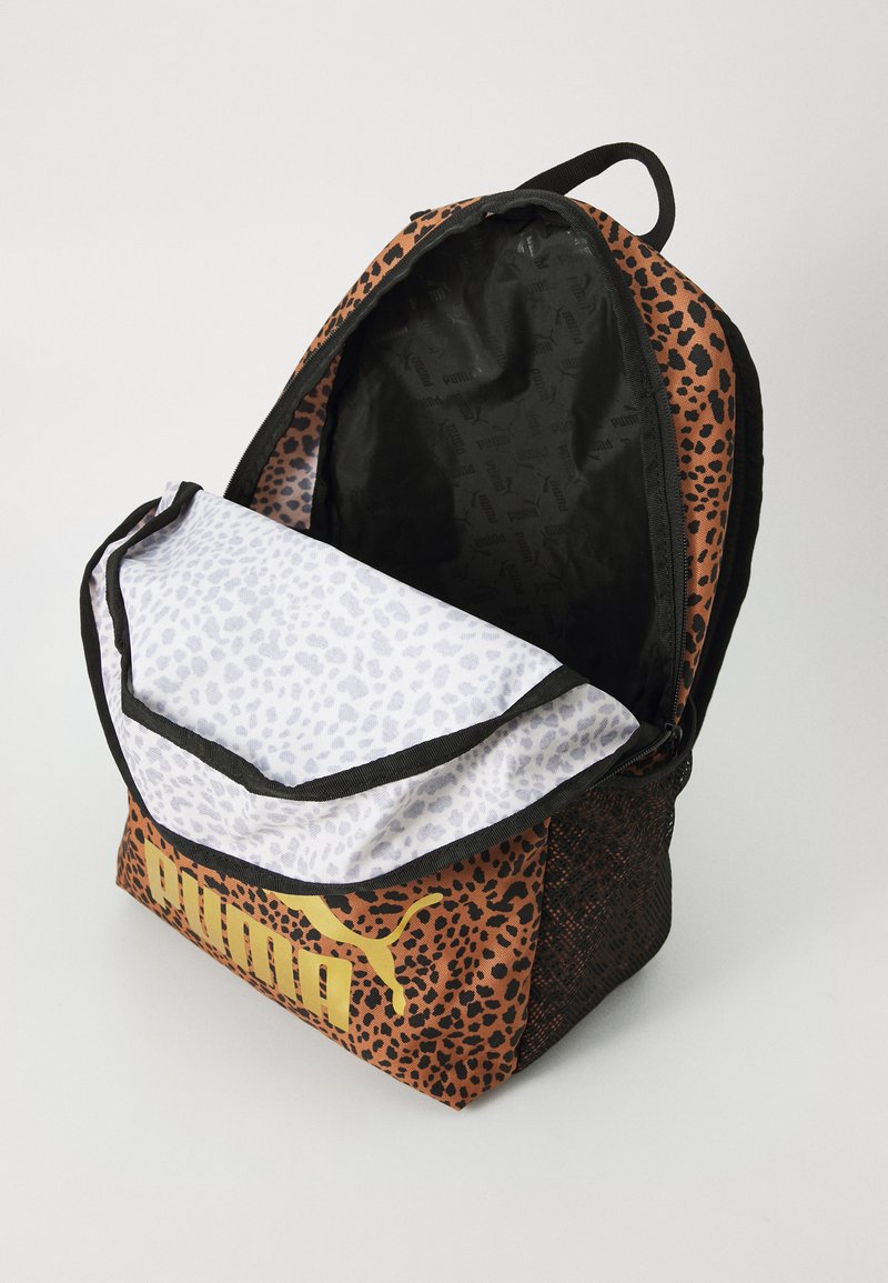 Mochila PUMA con un diseño de estampado de leopardo marrón, acentos negros y un forro interior blanco que presenta un sutil patrón animal. Logo dorado exhibido.