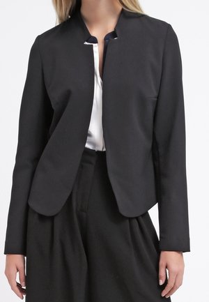 Blazer noir sans col avec une coupe ajustée, texture lisse et design à ouverture avant. Il présente des manches longues et un style minimaliste.
