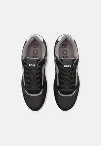 Zapatillas negras que combinan materiales de malla y ante, con acentos grises, seis ojetes y un collar acolchado con el logo "BOSS".