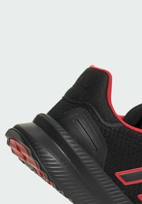 Czarny but sportowy z czerwonymi akcentami; siateczkowa cholewka, wyściełany kołnierz, teksturowana podeszwa i detal logo na śródpodeszwie.
