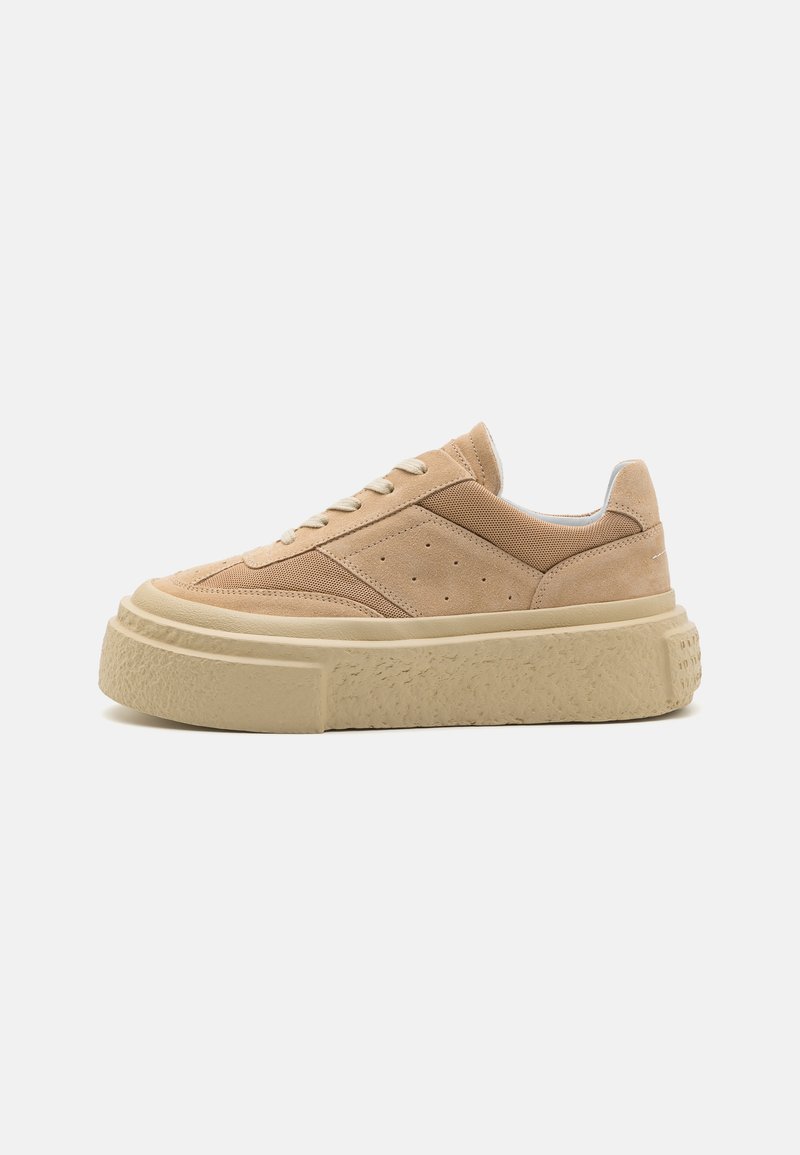 Beige suede sneakers with mesh accents, rounded toe, and a thick, textured off-white sole. Features perforations on the side.