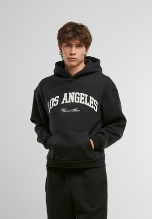Black hoodie with white "LOS ANGELES" text across the chest, featuring a front kangaroo pocket and ribbed cuffs and hem.