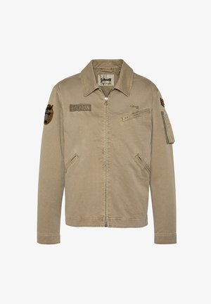 Veste Schott marron clair à fermeture éclair avec col, patchs sur la poitrine et les manches, poches zippées sur la poitrine, les manches et les côtés.
