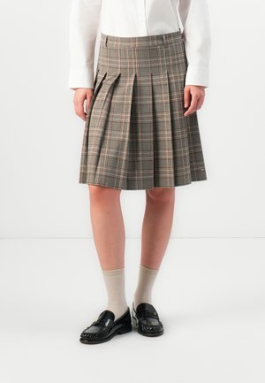 Foldsjørt i grå og beige toner, laget av stoff med en myk tekstur. Brukt med svarte loafers og beige sokker.