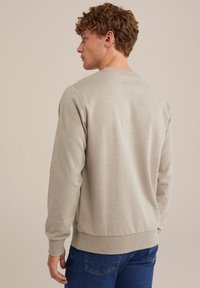 Hele halli crewneck sweatshirt, ribatud varrukate ja hemiga. Pehme tekstuur, klassikaline lõige ja minimaalsed õmblused, kantud siniste denim teksadega.