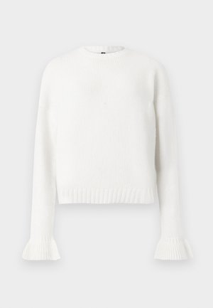 Jersey de punto blanco con canalé, cuello redondo, mangas largas y puños acampanados. Textura suave, longitud recortada y diseño sencillo.