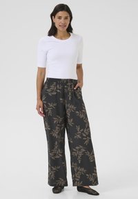 Black wide-leg trousers with a gold leaf pattern, elastic waistband, and side pockets. Paired with a fitted white short-sleeve top.