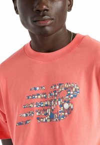 Camiseta de algodón coral con un diseño gráfico de formas de boyas coloridas en varios tamaños. Cuello redondo y mangas cortas.