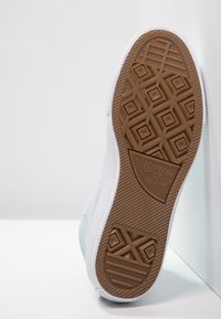 Podeszwa trampków Converse All Star z brązową gumową podeszwą zewnętrzną, płaskim, teksturowanym wzorem antypoślizgowym oraz białą podeszwą środkową.