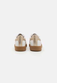 Hvite og metallisk gull sneakers med en glatt tekstur, avrundet form og gummisåle. Har en subtil logo på hælen.