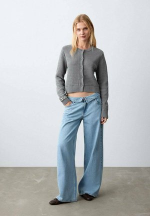Cardigan court gris en maille avec cinq boutons, associé à un jean à jambes larges bleu clair et des ballerines marron. Design simple, texture douce.