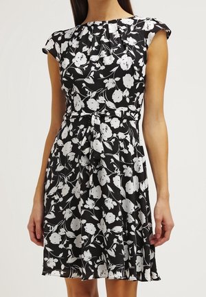 Abito nero con stampa floreale bianca, maniche a cappuccio, scollatura plissettata e vita legata. Realizzato in tessuto leggero con un design fluente.