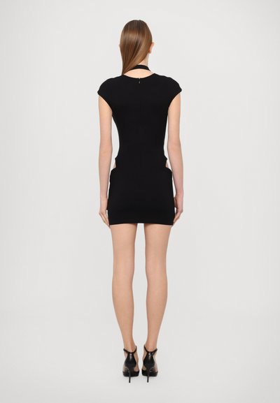 Rochie neagră, ajustată, cu mâneci scurte, decupaje laterale și fermoar la spate. Material texturat, elastic. Asortată cu pantofi cu toc înalt negri.