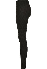 Leggings noirs avec un motif texturé en nid d'abeille, taille haute et coupe ajustée, fabriqués à partir d'un matériau extensible et léger.