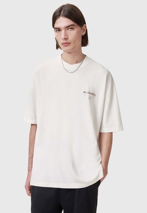 Hvid bomulds T-shirt med afslappet pasform, rund halsudskæring, korte ærmer og subtilt "A.L.L. SAINTS" logo på brystet. Glat tekstur.