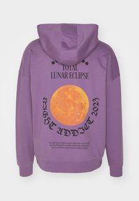 Sudadera con capucha morada que presenta un gran gráfico de la luna naranja en la parte trasera, con texto negro que dice "ECLIPSE LUNAR TOTAL" y "ADICTO A LA NOCHE 2023".