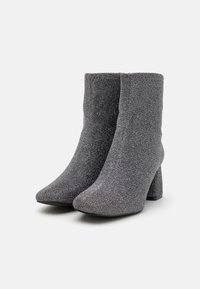 Grå glitter ankelstøvler med teksturfinish, spiss tå og blokkheel. Laget av et elastisk stoff for en tettsittende passform.