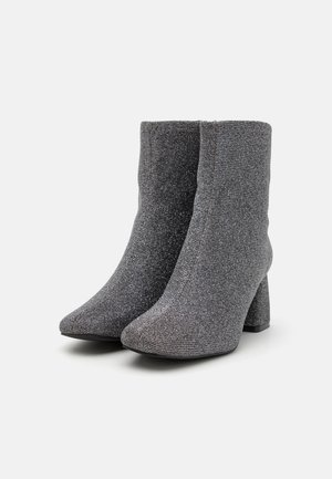 Gray glitter ankle boots with a textured finish, pointed toe, and block heel. Made from a stretchy fabric for a snug fit.