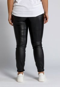 Zwarte neplederen broek met een slim fit, voorzien van enkelsluitingen en een gladde textuur. Draag het met een wit T-shirt en witte sneakers.
