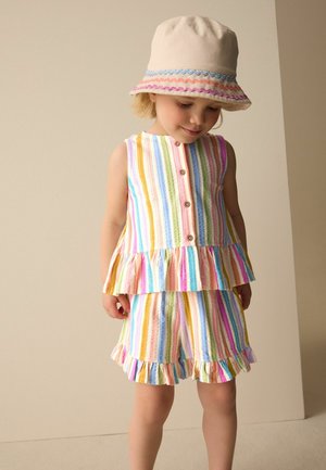 Fiatal gyermek ujjatlan, gombos, szivárványszínű csíkos felsőben és hozzáillő fodros rövidnadrágban, valamint bézs kalapban, színes szegéllyel.