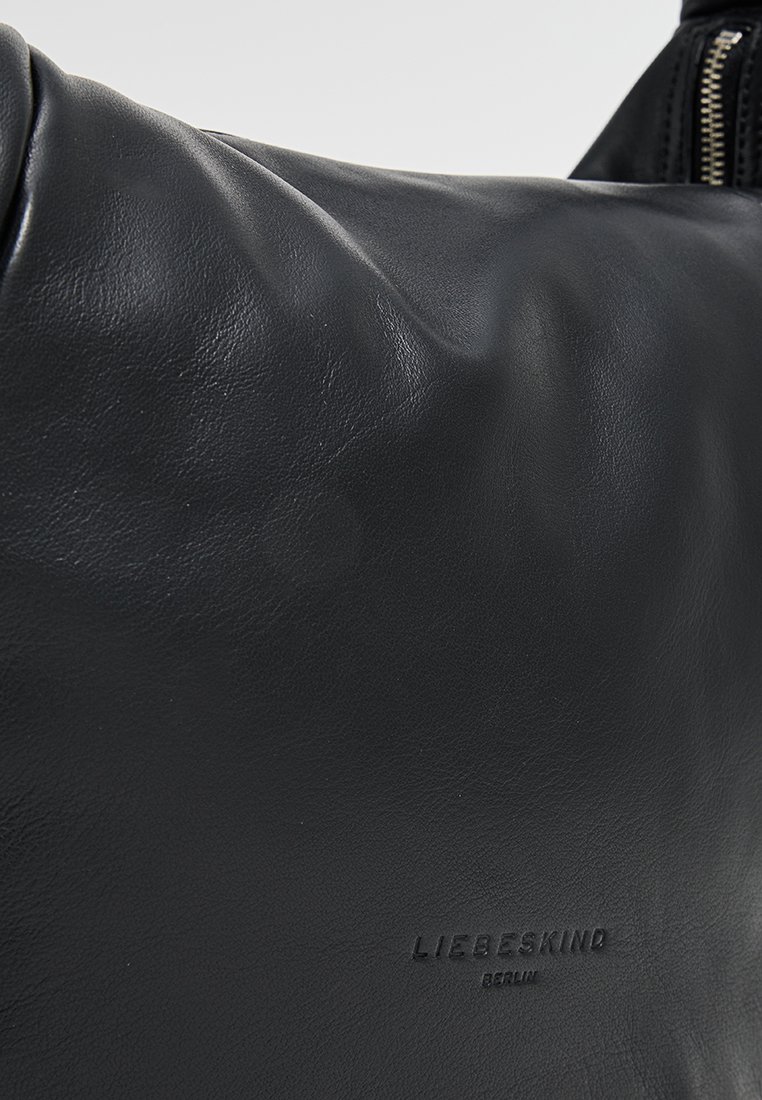 Schwarze Lederhandtasche mit einer weichen Textur, ausgestattet mit einem geprägt Markenlogo und einem Abschnitt aus Metallreißverschluss. Glattes und minimalistisches Design.