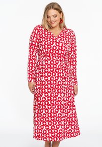 Rotes und weißes Wickelkleid mit langen Ärmeln, das ein florales Muster aufweist und einen Bindegürtel in der Taille hat, gefertigt aus einem weichen, dehnbaren Stoff.