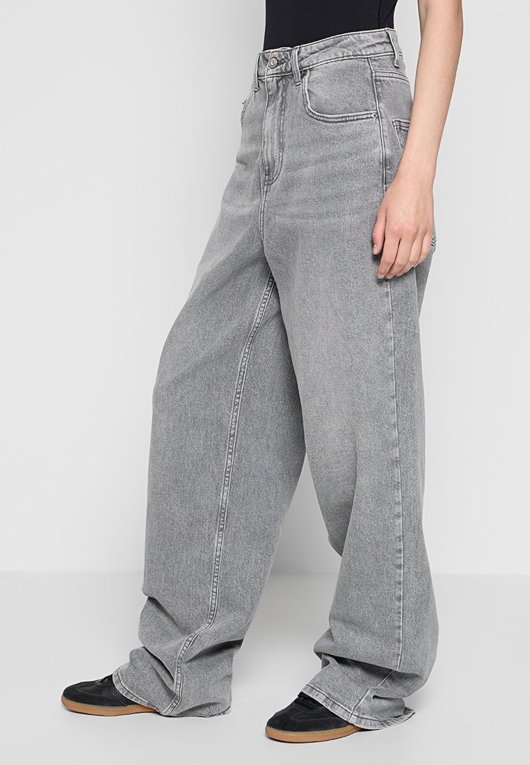Jeans grigi a gamba ampia con vita alta, caratterizzati da una texture in denim sbiadito, cinque tasche e una chiusura tradizionale con bottone e zip.
