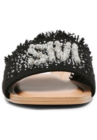 Sandalo slide in tessuto nero con bordo sfilacciato, caratterizzato da lettering e decorazioni in perline argento sulla parte superiore. Suola beige.