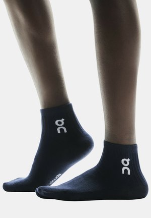 Marineblauwe enkelsokken met een gestructureerde afwerking, voorzien van een wit logo op de zijkant en een geribde boord voor een goede pasvorm en comfort.