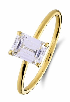 Gouden ring met een rechthoekige smaragd geslepen heldere edelsteen, vastgehouden door vier pootjes op een dun, gepolijst bandje tegen een witte achtergrond.
