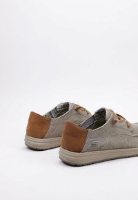 Zapatos informales de lona beige con detalles en ante marrón, presentan un diseño texturizado y un forro interior con estampado, suela de perfil bajo.