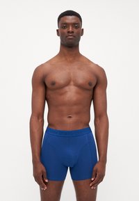 Boxers en coton bleu avec une ceinture texturée portant le logo "BJÖRN BORG". Tissu lisse, design ajusté et longueur mi-cuisse.