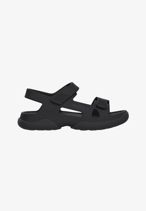 Sandalias negras con material sintético, puntera cerrada, correas ajustables y suela texturizada. Presenta recortes para mayor transpirabilidad.