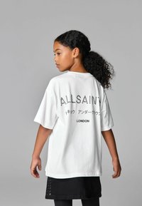 Bílý bavlněný tričko s černým textem "ALLSAINTS" a japonskými znaky a nápisem "LONDON" na zádech; volný střih a krátké rukávy.
