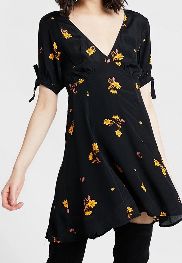 Svart blommigt klänning med v-ringning, korta puffärmar och draperade detaljer. Har en flödande silhuett med gula och rosa blommönster.