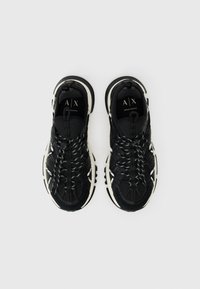 Black athletic shoes with a textured fabric upper, elastic laces, white accents, and a cushioned sole. Features logo on the tongue.