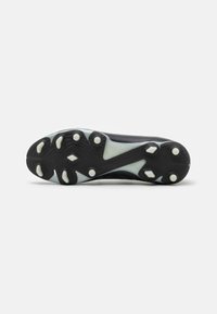 Suela de zapato de fútbol negra y elegante con diversos patrones de tacos, superficie texturizada y acentos blancos, diseñada para un buen agarre en el campo.