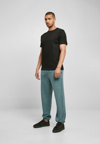 Svart bomull T-skjorte og lyseblå joggebukser med elastiske mansjetter, kombinert med svarte joggesko. Enkelt design med en avslappet passform.