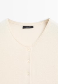 Creamfarbener Cardigan aus weichem Stoff mit rundem Halsausschnitt, mit einer Knopfleiste mit vier Knöpfen und einem Innenetikett.