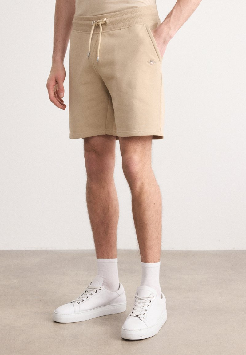 Beige pamut keverék rövidnadrág elasztikus derékkal és zsinórral, oldalsó zsebekkel és egy kis logóval a bal oldalon.