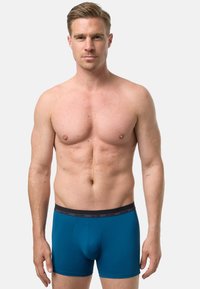 Pánské boxerky v jednobarevné tyrkysové barvě s černým elastickým pasem zdobeným jemným vzorem. Hladká látka, přiléhavý střih a délka po střed stehna.