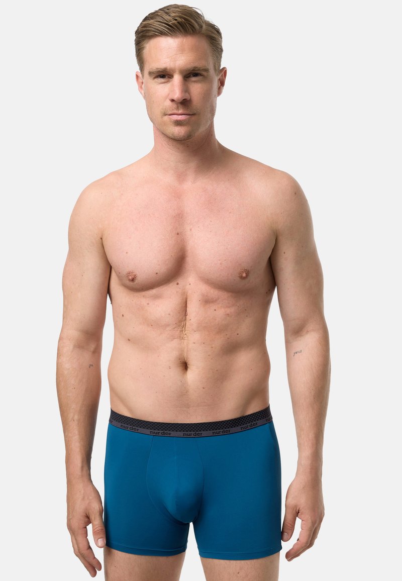 Pánské boxerky v jednobarevné tyrkysové barvě s černým elastickým pasem zdobeným jemným vzorem. Hladká látka, přiléhavý střih a délka po střed stehna.