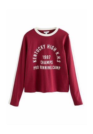 Czerwona koszulka z długim rękawem w białe paski, z graficznym nadrukiem "KENTUCKY HIGH K.H.S 1987 CHAMPS PRO RUNNING CAMP" z przodu.