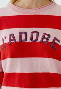 Rot- und pink gestreifter Pullover mit dem eingestickten Schriftzug "J'ADORE" in mehrfarbiger Stickerei, mit rundem Ausschnitt und weicher Textur.