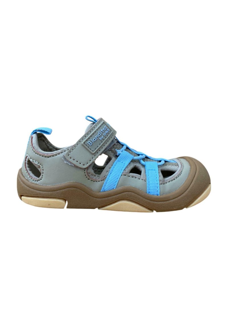 Sandalia gris para niños con correas azules, lados de malla transpirable, cierre de Velcro y suela de goma con un diseño ondulado.