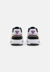 Scarpe sportive bianche e nere con accenti viola, caratterizzate da una tomaia in rete e dettagli in suede testurizzati sul tallone, progettate per il comfort.